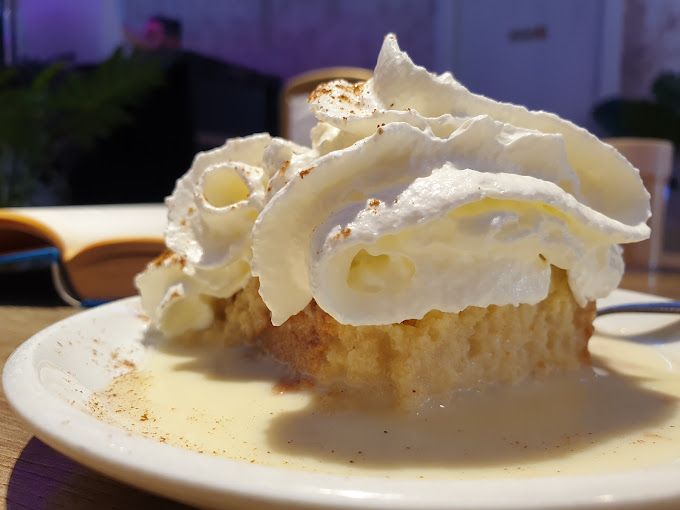 Un trozo de pastel con crema batida encima en un plato.