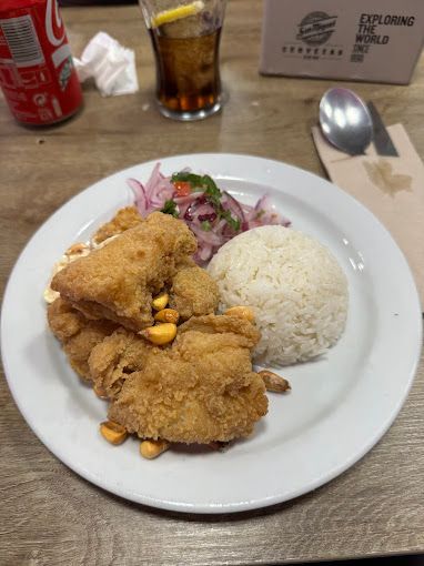 Un plato de comida con arroz y pollo frito en una mesa.