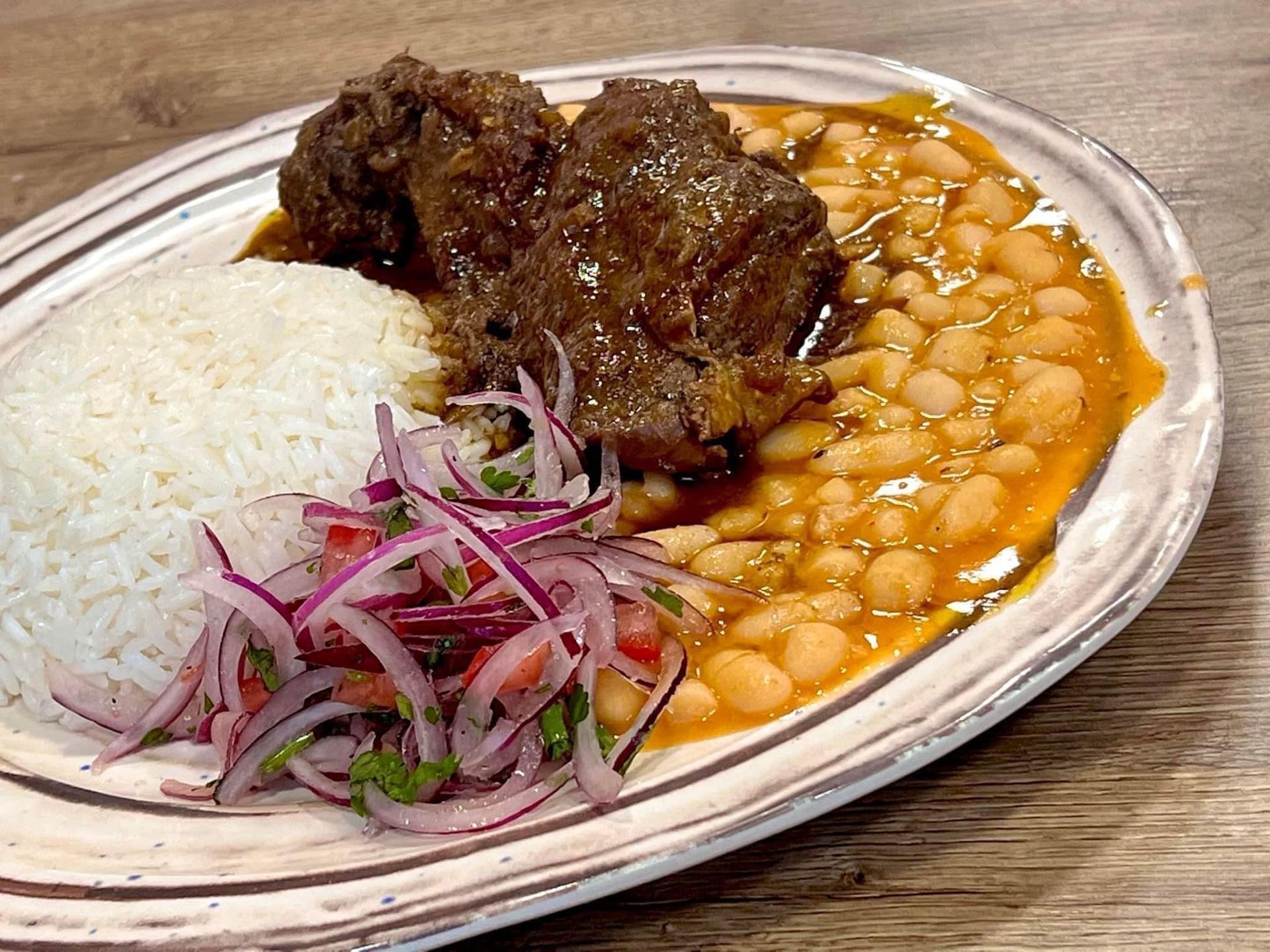 Un plato de comida con frijoles y arroz en una mesa de madera.