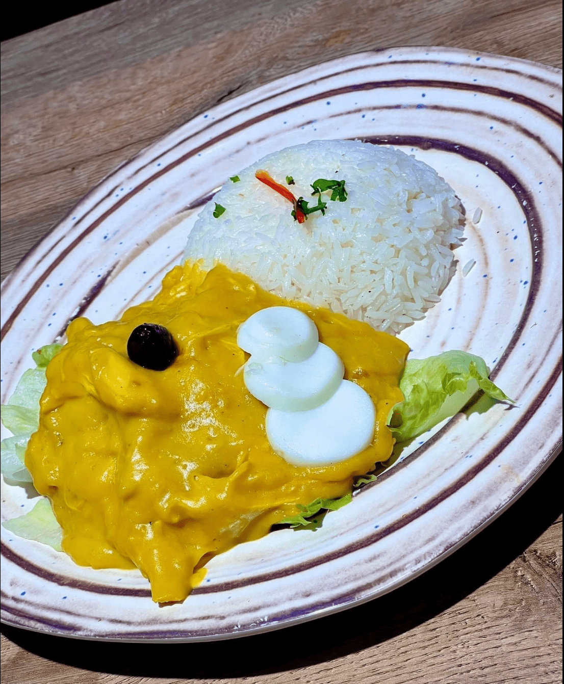 Un plato de comida con arroz y salsa en una mesa.