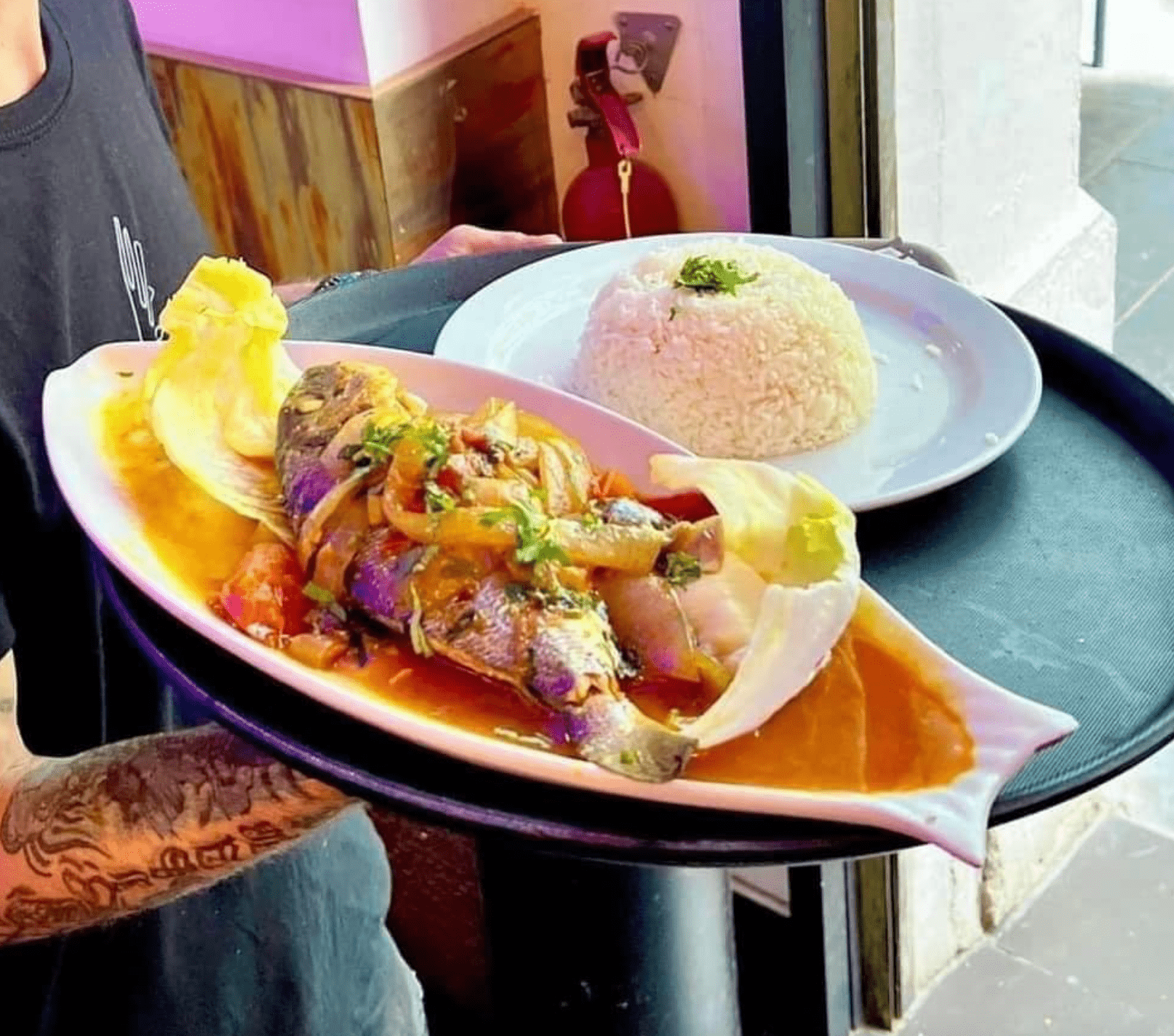 Una persona sostiene una bandeja con platos de comida encima.