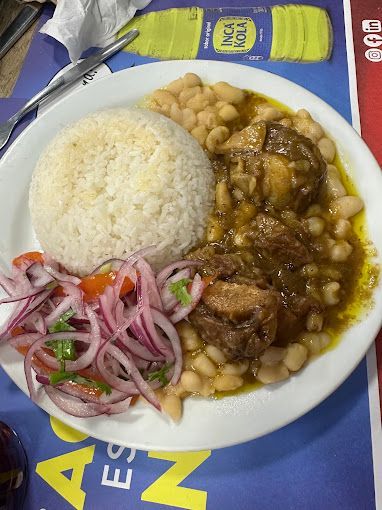Un plato de comida con arroz, frijoles y cebollas en una mesa.