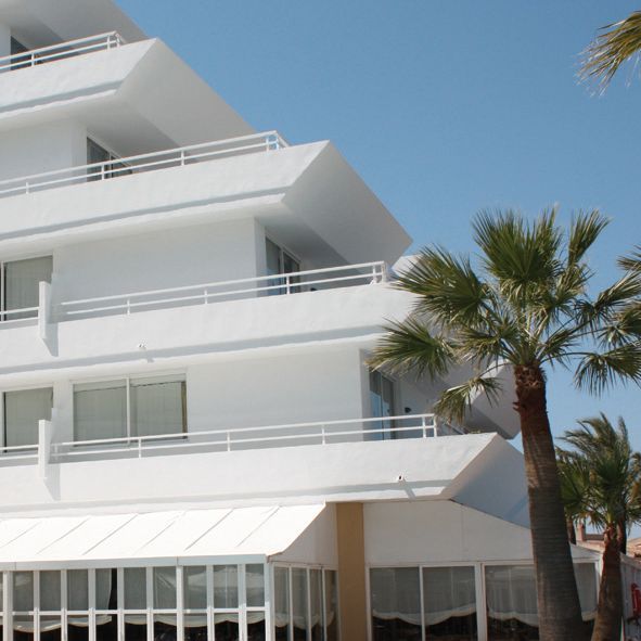 Un edificio blanco con palmeras delante.