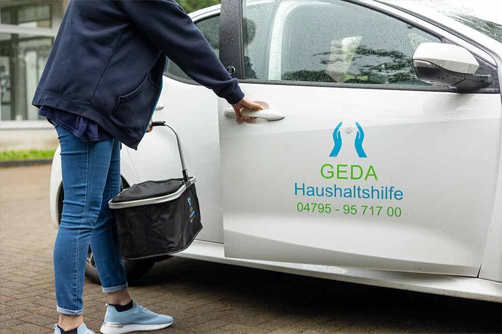 Eine Frau öffnet die Tür eines weißen Autos.