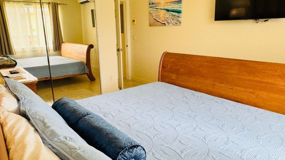 Bedroom with a large bed in the foreground and a second bed reflected in a mirror.