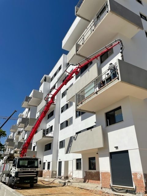 Un edificio blanco con una grúa roja adjunta.