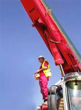 Un hombre está parado encima de una grúa roja.