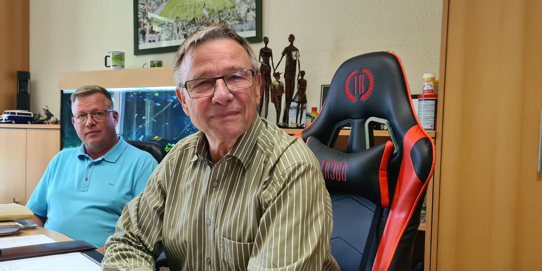 Ein Mann in einem grünen Hemd sitzt in einem Gaming-Stuhl