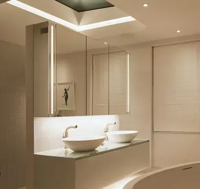 Baño moderno, blanco, con dos lavabos, espejos e iluminación suave.