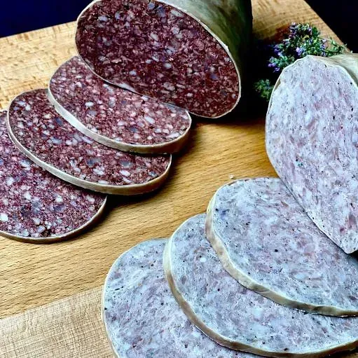 Rodanxes de botifarra de sang i botifarra blanca sobre una taula de tallar de fusta.