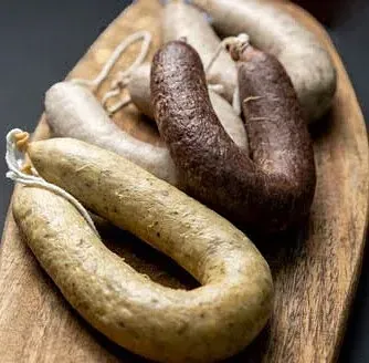 Salsitxes variades de diferents colors i textures sobre una taula de tallar de fusta.