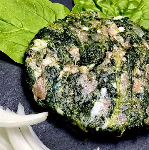 Hamburguesa d'espinacs i carn amb fulla d'espinacs, ceba, superfície fosca.