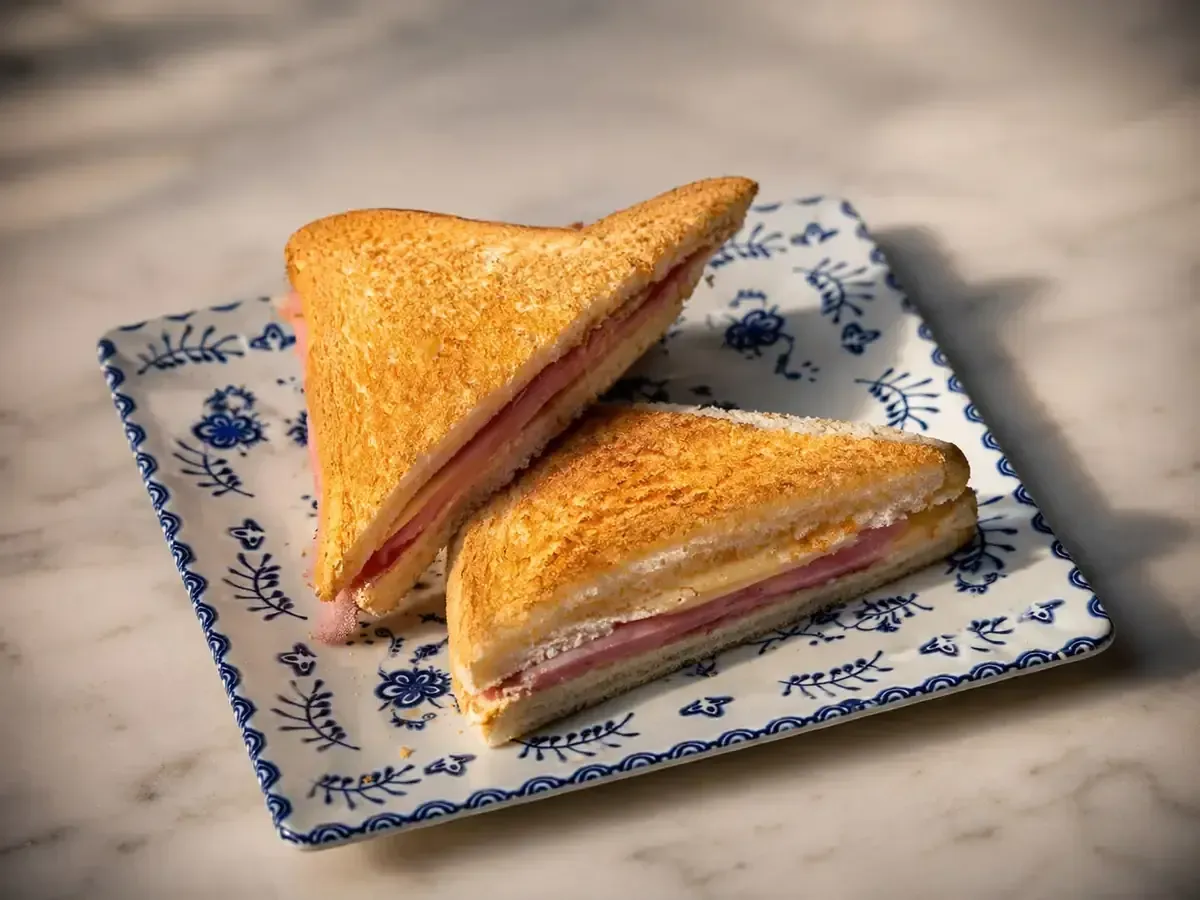 Café, zumo de naranja, cruasán, gofres y fresas sobre una mesa oscura con un fondo de neón en forma de anillo.