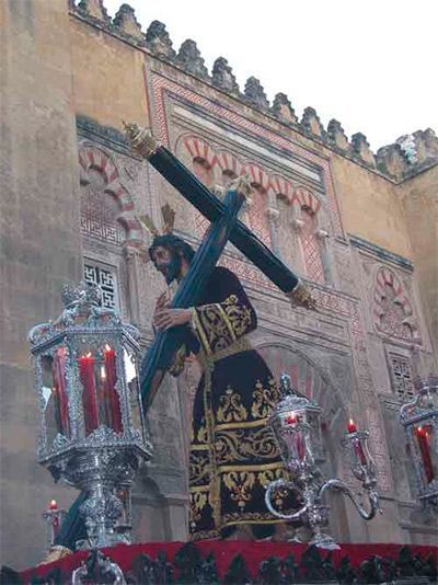 Una estatua de Jesús llevando una cruz frente a un edificio.