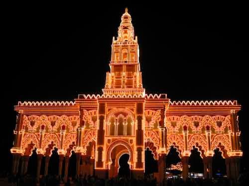 Un gran edificio está iluminado con luces naranjas por la noche.