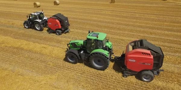 Tres tractores están empacando heno en un campo.