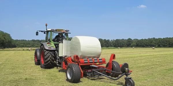 Un tractor está empacando heno en un campo.