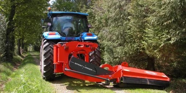 Un tractor azul y rojo circula por un camino de tierra.