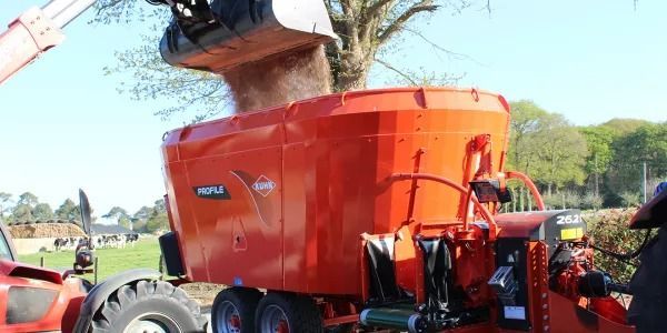 Un tractor rojo se carga con tierra desde un mezclador.