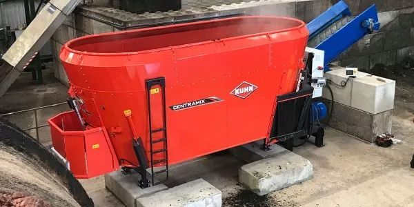 Una batidora roja está colocada encima de un bloque de hormigón en una habitación.