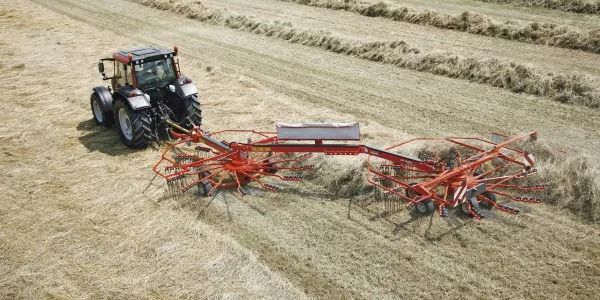 Una vista aérea de un tractor tirando de un rastrillo de heno en un campo.