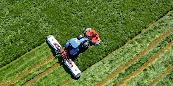 Una vista aérea de un tractor cortando césped en un campo.