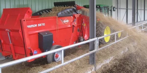 Un tractor está cargando heno en un remolque en un granero.