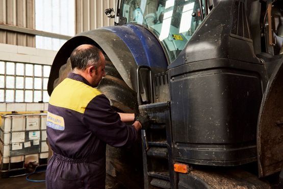Un hombre está trabajando en un tractor en un garaje.
