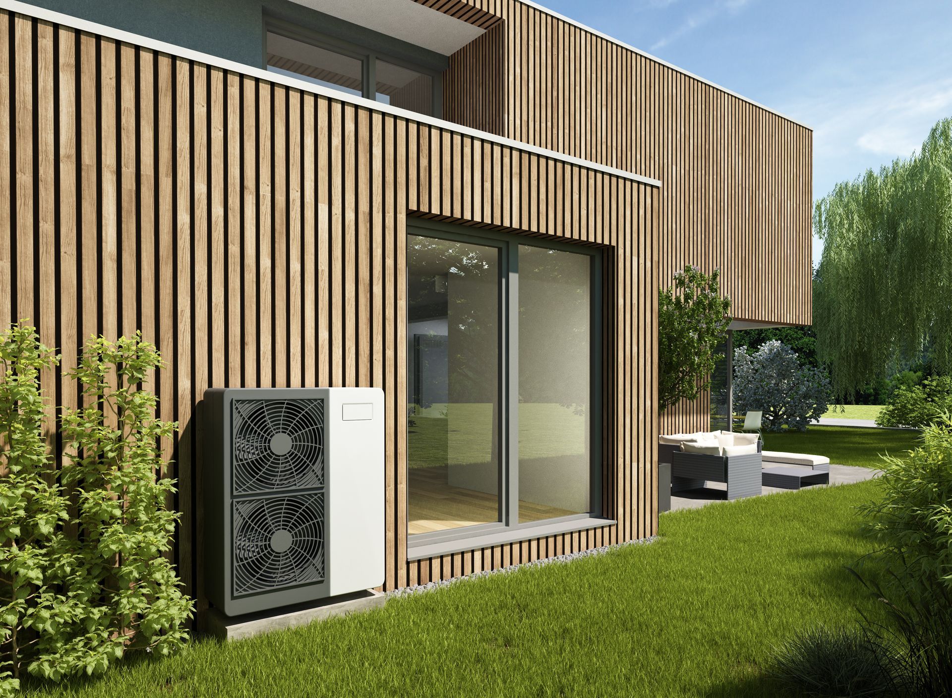 Extérieur d'une maison moderne en bois avec de grandes fenêtres, pelouse et coin salon extérieur par une journée ensoleillée.