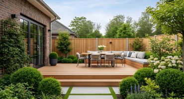 Patio moderne dans le jardin avec terrasse en bois, ensemble de repas extérieur, canapé et aménagement paysager luxuriant à côté d'une maison en brique.
