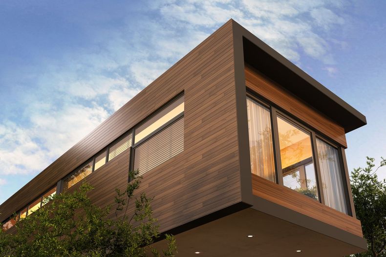 Maison moderne à deux étages avec bardage en bois et grandes fenêtres se détachant sur un ciel partiellement nuageux