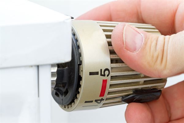 Eine Person hält einen Thermostat mit der Zahl 5 darauf