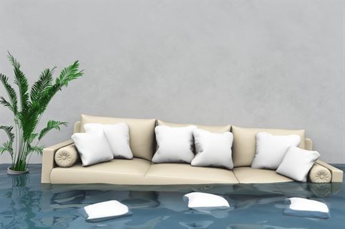 In einem überfluteten Raum schwebt eine Couch mit weißen Kissen.