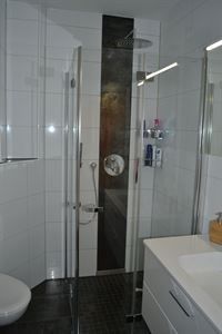 Ein Badezimmer mit Dusche, Waschbecken, Toilette und Spiegel.