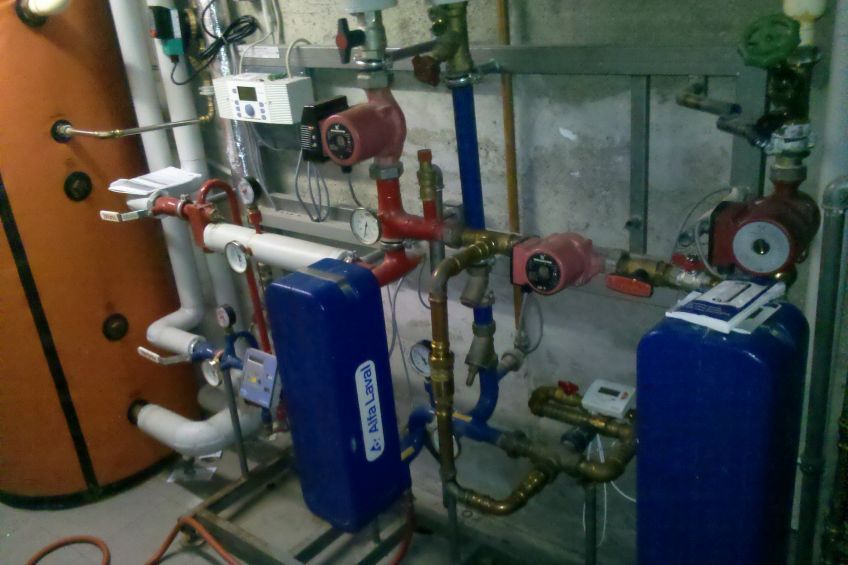 Ein Raum mit vielen Rohren und einem blauen Tank mit der Aufschrift „Caldaia“