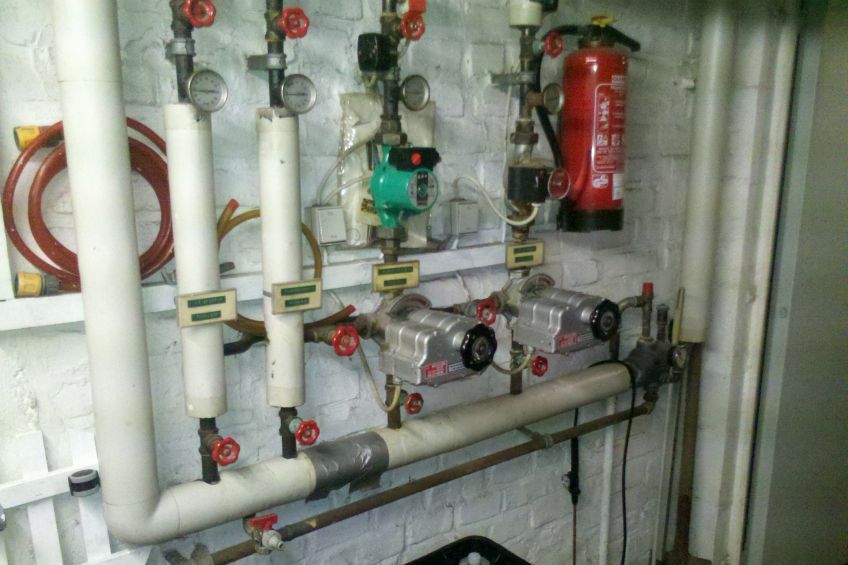 Ein Feuerlöscher hängt an einer Wand neben einem Bündel Rohre