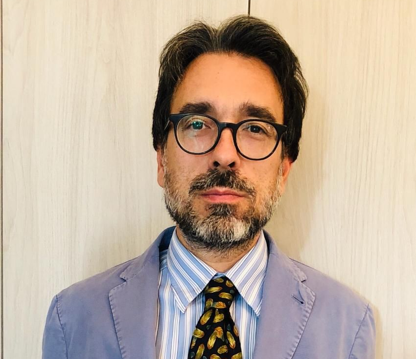 Un homme portant des lunettes, une cravate et un costume.