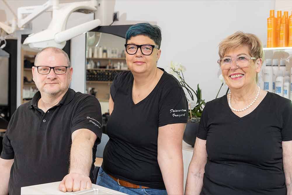 Eine Frau mit blauem und rosa Haar lächelt, während sie ihr Haar im Spiegel betrachtet.