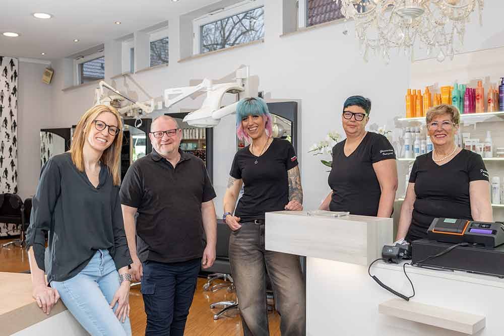 Eine Gruppe von Menschen posiert in einem Friseursalon für ein Foto.