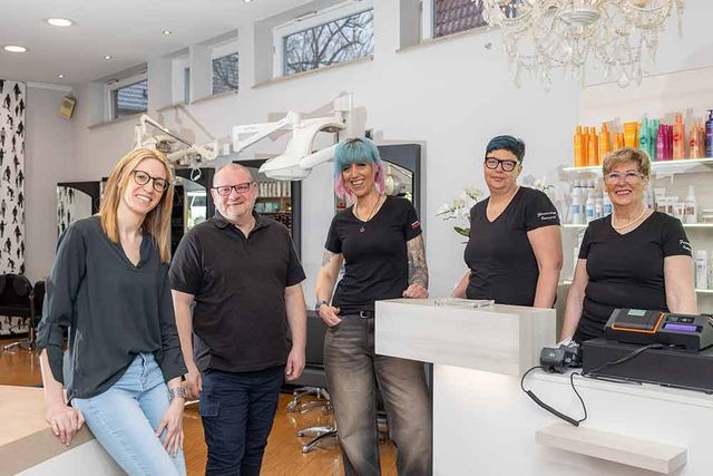 Eine Gruppe von Menschen posiert in einem Friseursalon für ein Foto.