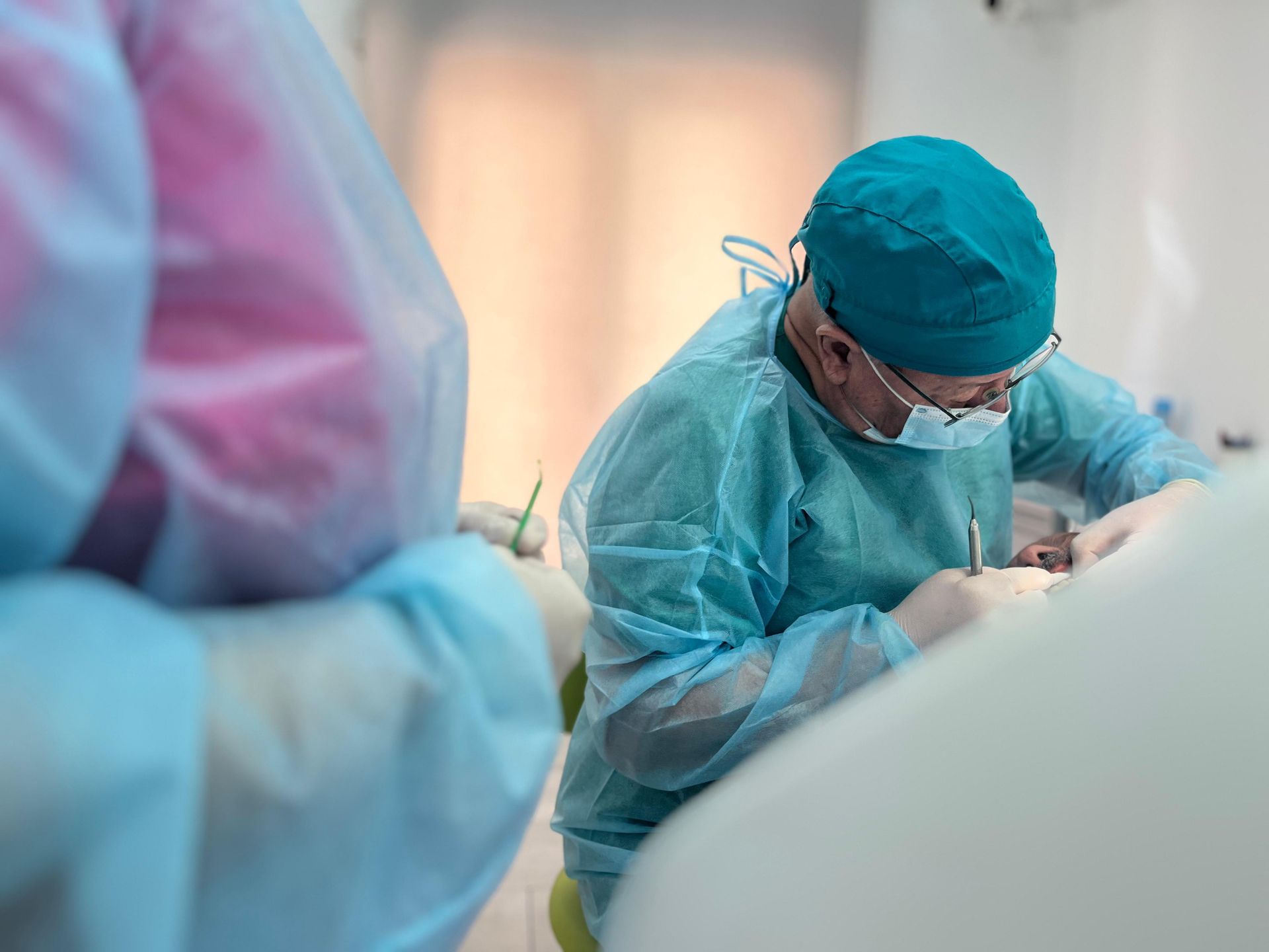 Un dentista está trabajando con un paciente en un consultorio dental.