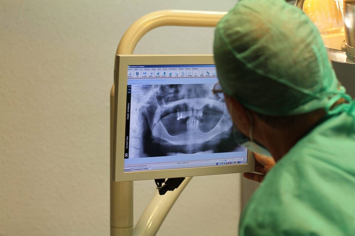 Una mujer con aparatos ortopédicos se hace examinar los dientes por un dentista.