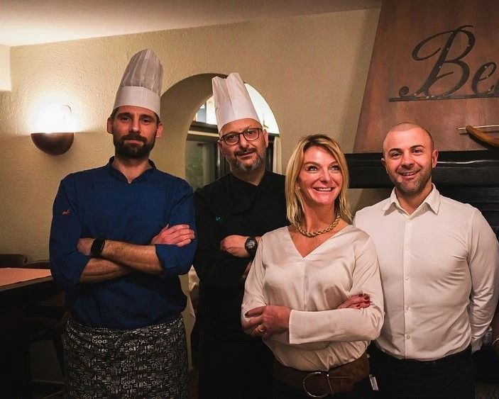 Tagliere di salumi e bicchieri da vino su un tavolo di legno, con vista panoramica sull'esterno.