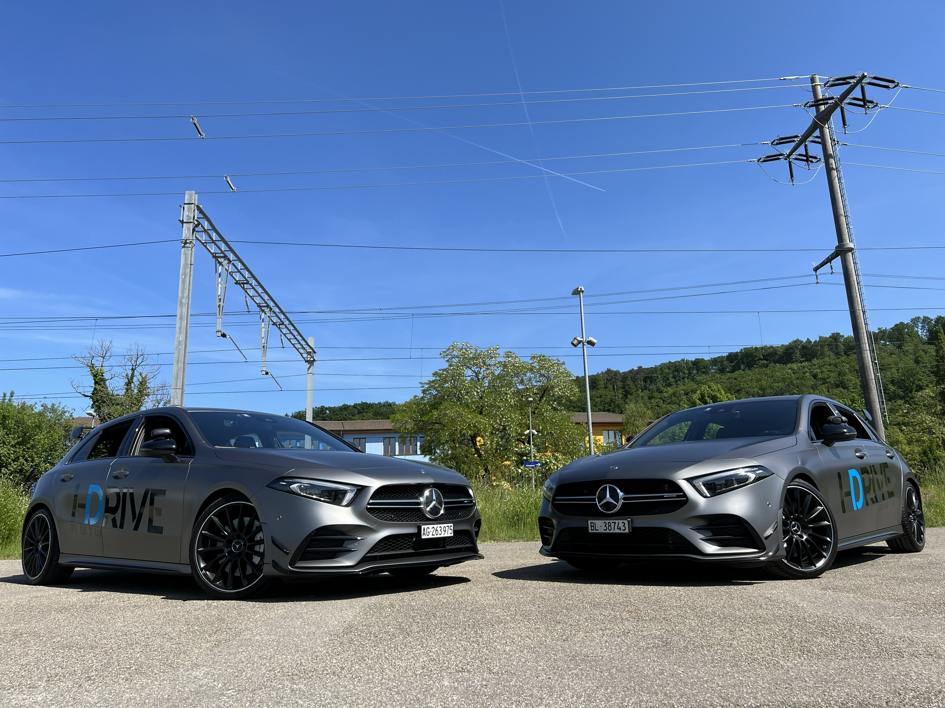 Zwei graue Mercedes-Fahrzeuge parkten nebeneinander auf einem sonnigen Parkplatz unter blauem Himmel.
