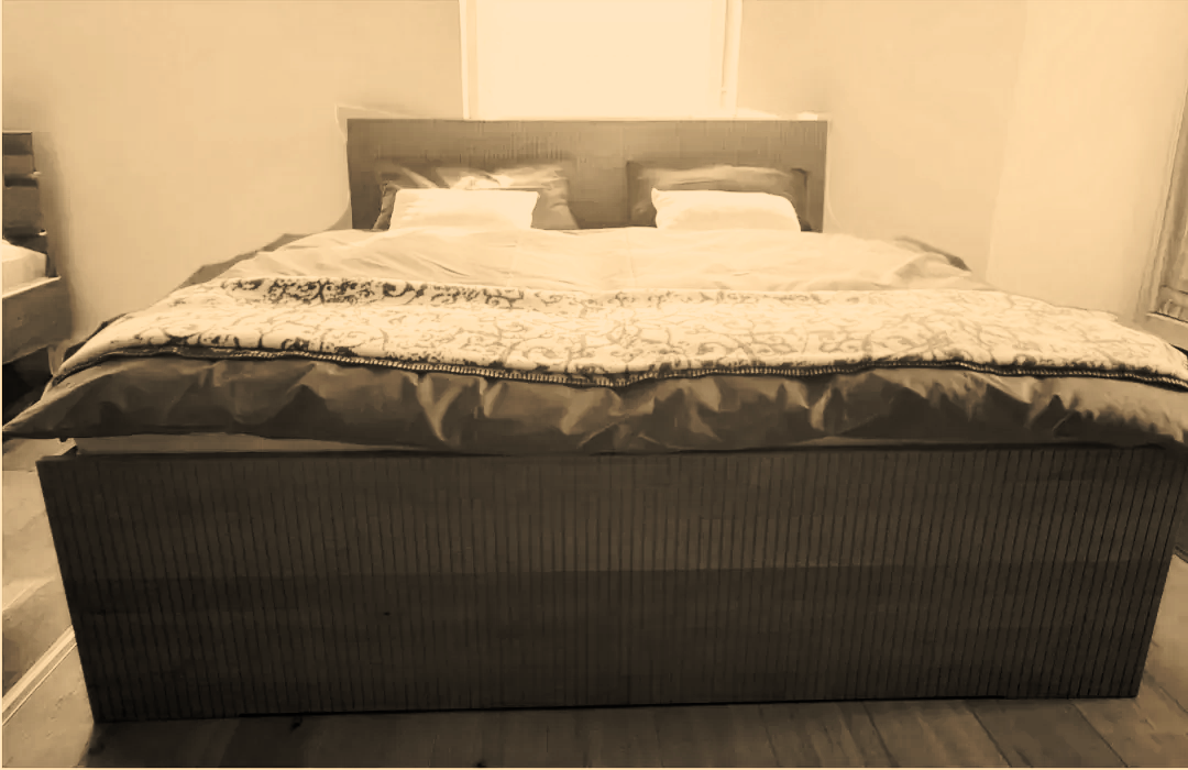 Ein ordentlich gemachtes Bett mit weißer Bettwäsche und Kissen in einem Schlafzimmer mit beigen Wänden und grauem Kopfteil