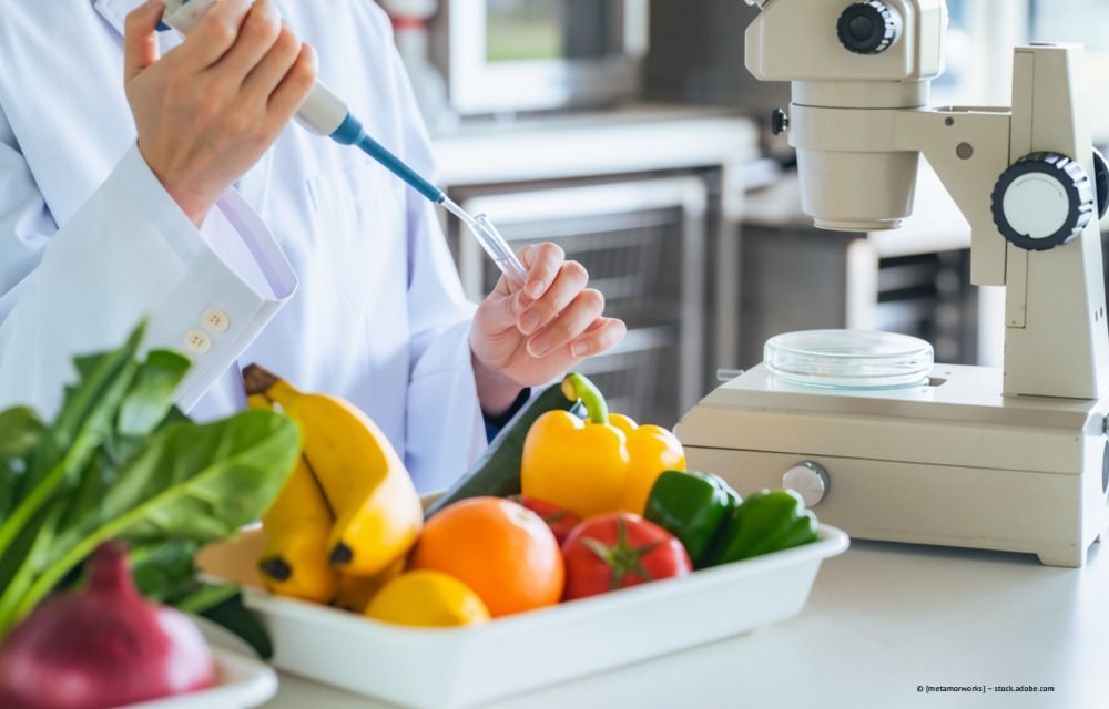 Wissenschaftler benutzt eine Pipette neben farbenfrohem Obst und Gemüse in einer Laborumgebung