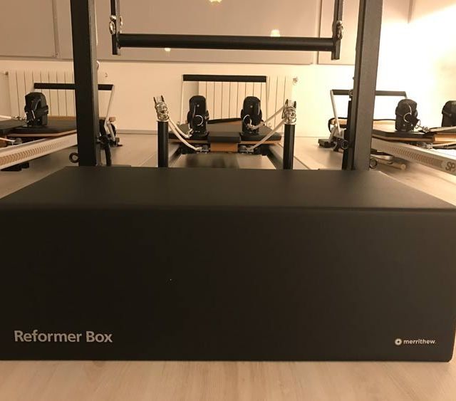 Caja negra para máquina de Pilates Reformer en un estudio con máquinas Reformer al fondo.
