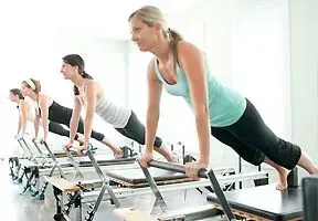 Personas haciendo ejercicio en máquinas de Pilates en un estudio luminoso.