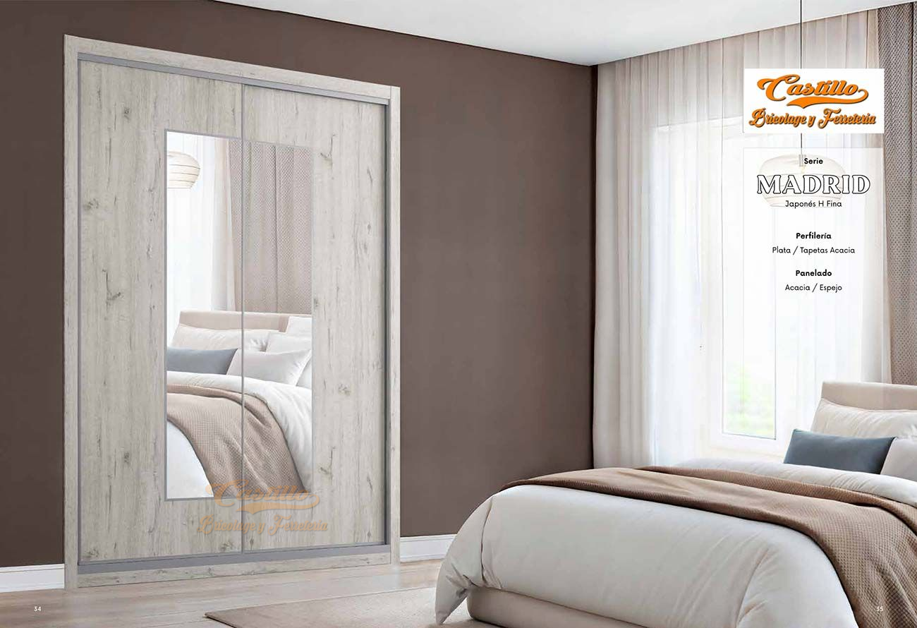 Dormitorio con un amplio armario con espejo de cuerpo entero, cama y ventana con cortinas transparentes.