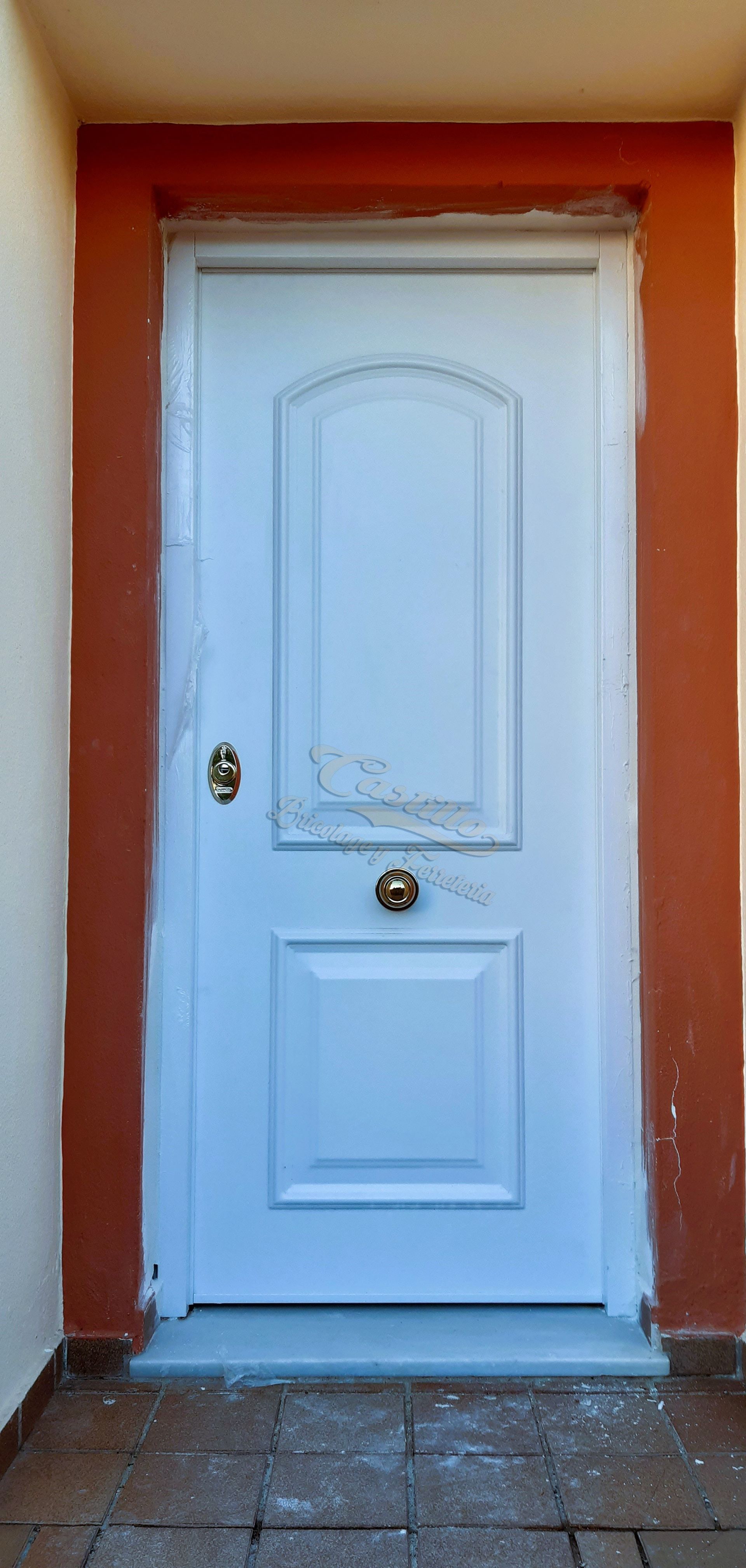 Una puerta blanca con un borde rojo está en un edificio.